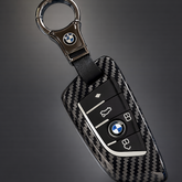 Carbon fiber key fob cover with BMW logo on a dark background